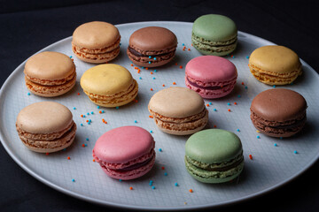 Macarons de colores sobre fondo negro. Concepto gastronomía repostería. 