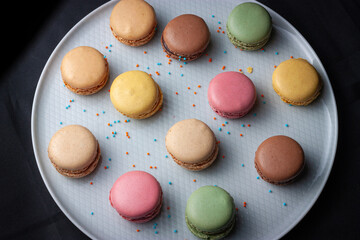 Macarons de colores sobre fondo negro. Concepto gastronomía repostería. 