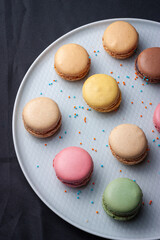 Macarons de colores sobre fondo negro. Concepto gastronomía repostería. 