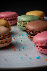 Macarons de colores sobre fondo negro. Concepto gastronomía repostería. 