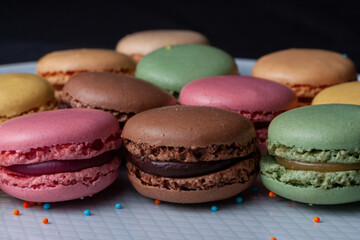 Macarons de colores sobre fondo negro. Concepto gastronomía repostería. 