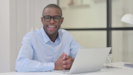 African Man with Laptop Smiling at Camera 