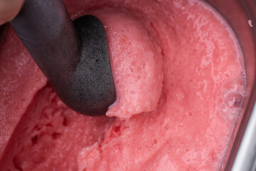 Closeup of refreshing frozen sweet berry ice cream desert in container with spoon