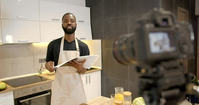 African american chef with recipes book in kitchen