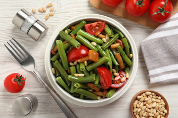 Delicious salad with green beans, mushrooms, pine nuts and tomatoes served on white wooden table,...