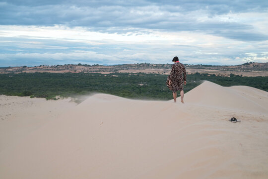 Wanderer walking in the desert. Young man standing in white sand dunes. Backside view. Stranger in desert. High quality photo