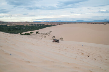 Amazing view of parked motorbike on sandy dunes in desert. Sunny day during summer vacation. Sand dunes. Motorcycle in desert.