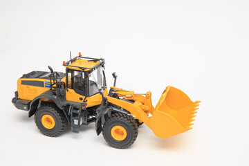 Obraz na płótnie Canvas Highly detailed yellow single-bucket forklift, scale model of specialized equipment on white background, bulk loader.