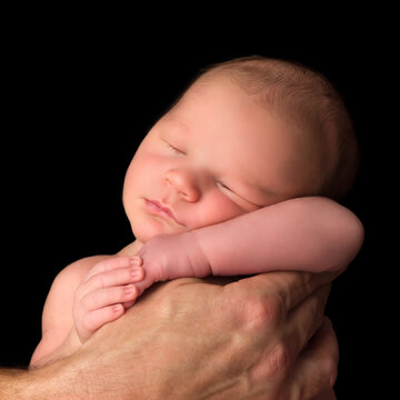 Closeup of a newborn little boy posed in Dad's hands