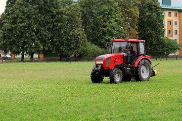 Red tractor mows the grass, mowing the lawn