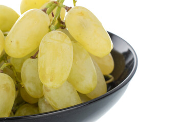 One bunch of organic juicy green grapes with black ceramic crockery, close-up, isolated on white.