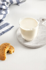 cookies and milk in a glass on a white table with a napkin