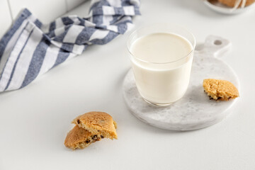 cookies and milk in a glass on a white table with a napkin