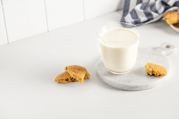 cookies and milk in a glass on a white table with a napkin