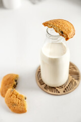 cookies and milk in a bottle  on a white table with a napkin
