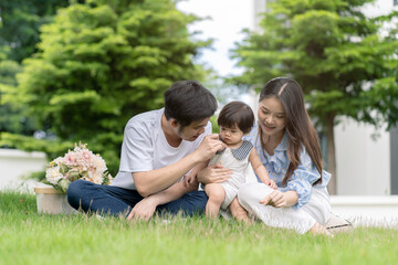 Naklejka na ściany i meble Asian Parents and a kid child playing in the garden at home. Family concept.