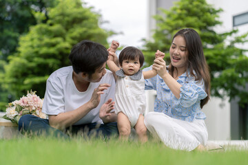 Asian Parents and a kid child playing in the garden at home. Family concept.