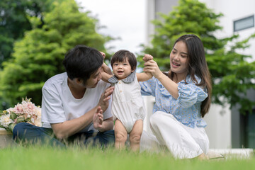 Asian Parents and a kid child playing in the garden at home. Family concept.