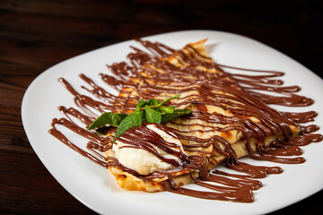 Pancake with a scoop of ice cream and chocolate. Close-up, selective focus