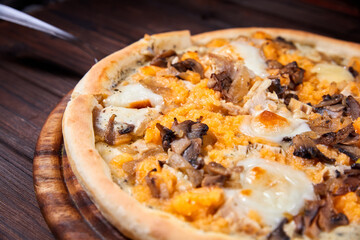 Pizza with cheese and mushrooms on a wooden plate. Close-up, selective focus