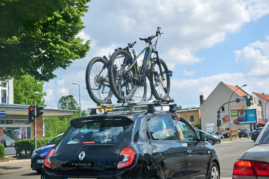 Berlin, Germany - July 3, 2021: Car with a bike carrier attached on the top and two bicycles mounted on it.