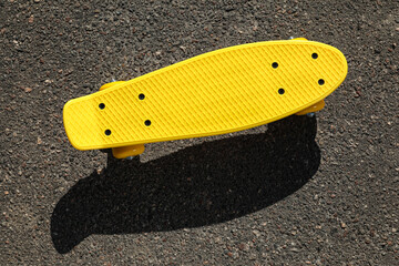 Modern yellow skateboard on asphalt road outdoors, top view © New Africa