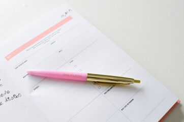 Planner for new years resolutions. Pink planner on a white desk. 
