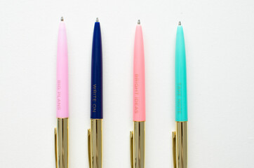 Colourful and gold pens on a white background. 