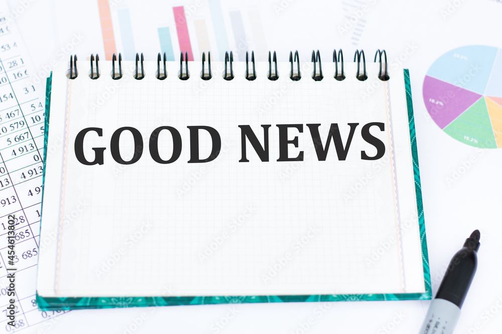 Fototapete Good news text on white notepad on table on the background of financial statements in the form of charts, business concept