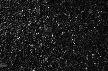 Industrial background consists of fine-grained anthracite coal in the dark.