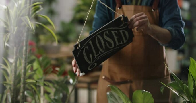 Flower shop employee flipping wooden board sign on glass entrance door. Small business, entrepreneurship concept 4k footage