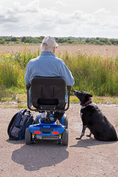 Man On His Mobility Scooter Taking A Rest With His Dog.