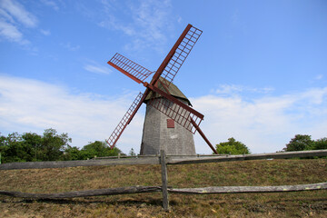 tall old gray windmill with spinning arms