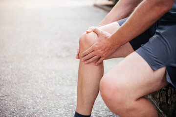 A man massaging his kneecap while suffering from patellofemoral joint pain