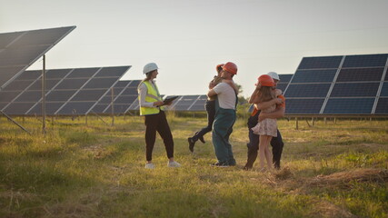 Two small children run to their parents who are at work. A solar power plant employee with children at work smiling at the camera. Three solar energy specialists at a solar power facility.