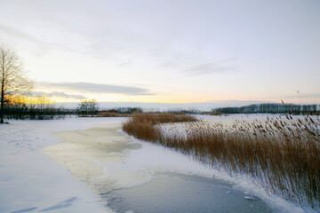 Beautiful winter landscape at sunset with fog and snow covering farmland and river in the Netherlands beautiful colors in nature