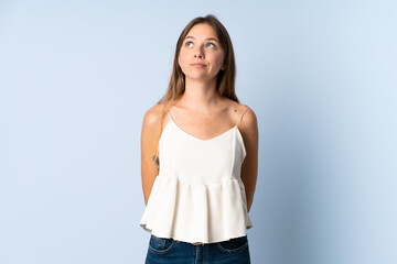 Young Lithuanian woman isolated on blue background and looking up