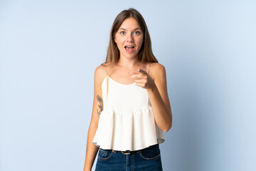 Young Lithuanian woman isolated on blue background surprised and pointing front