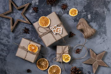 Wrapping rustic eco Christmas packages with brown paper, string and natural fir branches on dark background