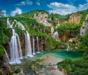 Plitvice, Croatia - Beautiful waterfalls of Plitvice Lakes (Plitvička jezera) in Plitvice National Park on a bright summer day with blue sky and clouds and green foliage and turquise water