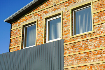 cladding of a brick house facade with corrugated sheet metal