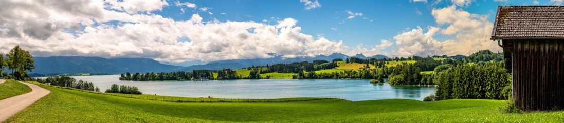Fototapeta na wymiar Breites Panorama mit Blick auf den Forggensee und die Berge der Alpen im Hintergrund