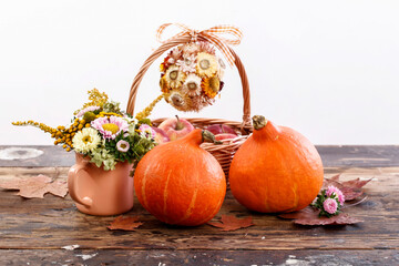 Pumpkins and autumn flowers on wooden table.