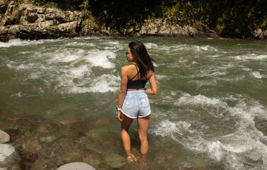 Young black woman tourist relaxes in river.