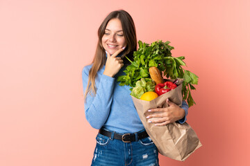 Young Lithuanian woman holding a grocery shopping bag looking to the side and smiling