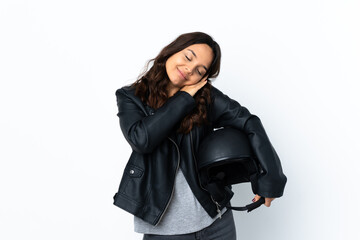 Young woman holding a motorcycle helmet over isolated white background making sleep gesture in dorable expression