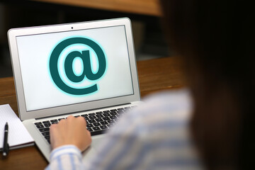 Woman sending email via laptop at table, closeup