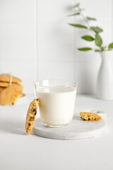 cookies and milk in a glass on a white table with little vase