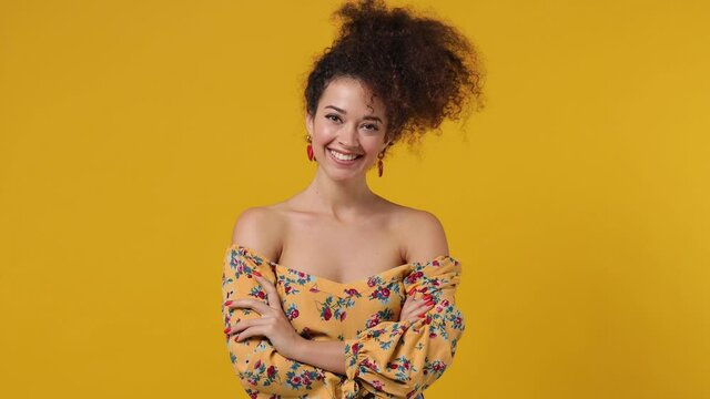 Happy blithesome charismatic stunning delight fancy young latin curly woman 20s wears casual flower dress looking camera smiling isolated on plain yellow background. People emotions lifestyle concept