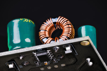 Printed circuit board with toroidal coil or green capacitors on black background. Through-hole...